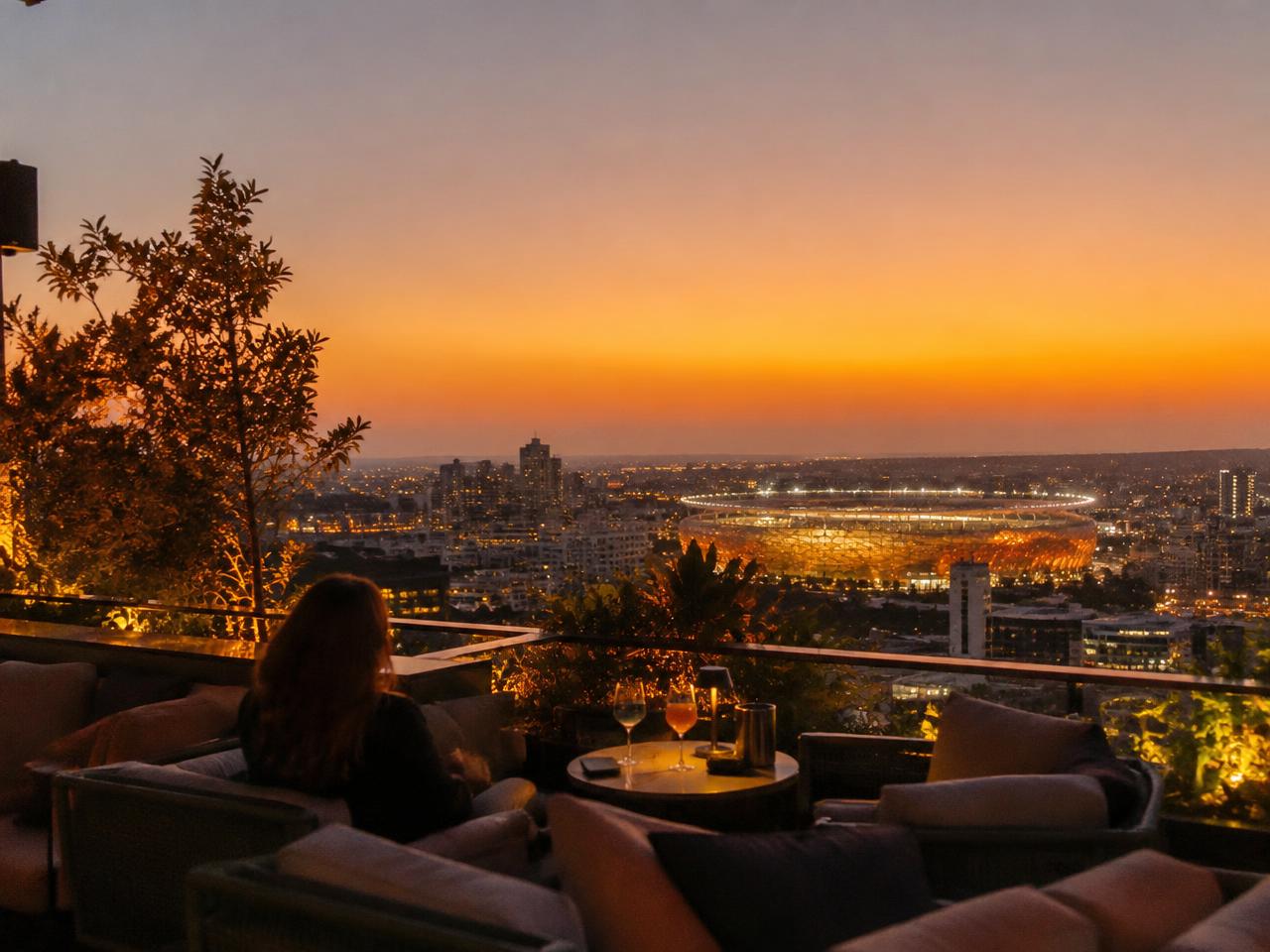 Rooftop bar overlooking a lit stadium